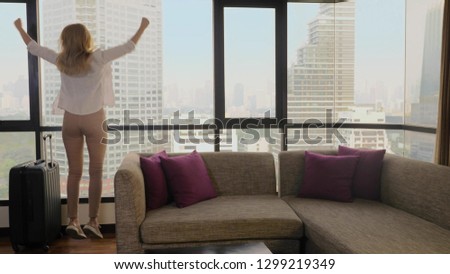 woman with a suitcase on the background of skyscrapers in a panoramic window