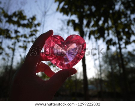 Silhouette pink heart in a lady hand. Sweet and bright plastic heart shape. Cute decoration for Valentine's day and another romantic moment.