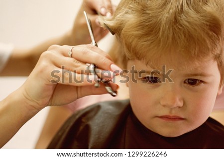 Hair salon that specializes in toddlers. Little boy with blond hair at hairdresser. Small child in hairdressing salon. Cute boys hairstyle. Hair salon for kids. Making haircut look perfect.