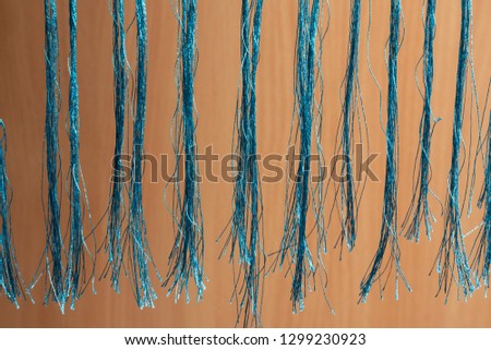Fringe of blue threads on a wooden beige background close-up.