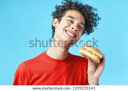Happily emotional guy holding a hamburger in his hand                 