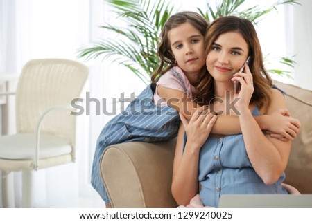 Portrait of young mother with little daughter at home