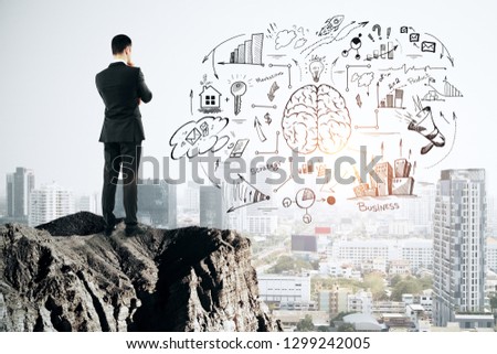 Back view of thoughtful young businessman looking at business sketch from cliff. City background. Brainstorming and finance concept 