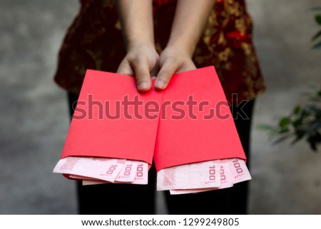 Woman dressing red qipao holding red angpao pockets with money in garden