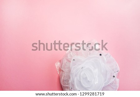 White ribbon bow on soft pink background. Festive decorative element.