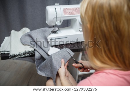 Workplace of seamstress. Dressmaker cuts dress detail on the sketch lines. Woman working with the machine for sewing.  Sewing Process