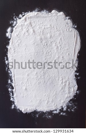 white flour sprinkled on a dark wooden table. top view