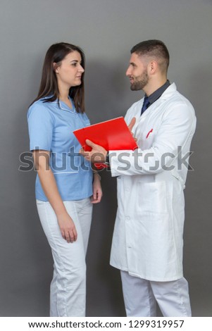 Male doctor and a female nurse posing on grey background.