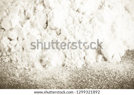 Pile of white wheat flour is scattered on an old worn cutting board. Toned.