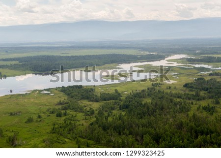 The rivers and lakes of Eastern Siberia from the altitude. A view from the cockpit of the helicopter to the lakes and the river in the Siberian taiga.
