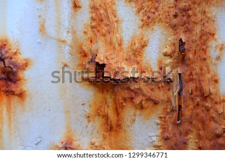 The rust on the container wall has peeling paint.