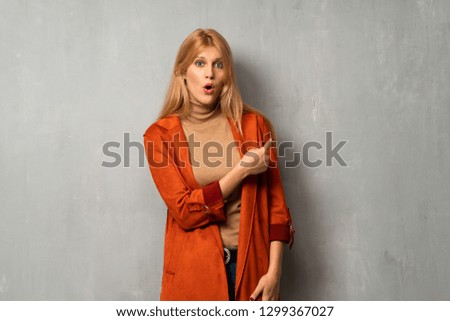 Woman over textured background surprised and pointing side