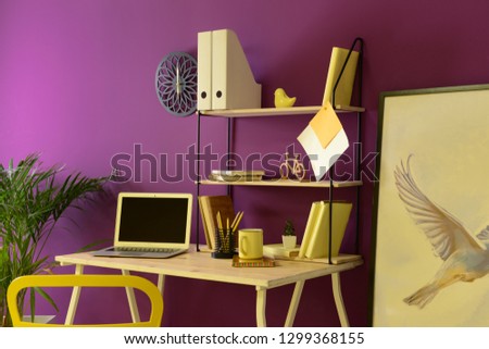 Stylish workplace with modern laptop near color wall