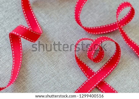 Heart made from red ribbon on linen fabric, Valentine's Day concept