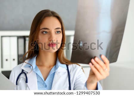 Beautiful female doctor hold in arm and look at xray photography portrait. Skeleton bone disease exam medic aid or cancer physical test in hospital for healthy lifestyle education career concept