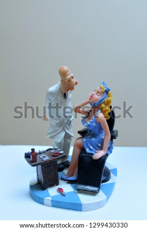 Clay figurine of a standing dentist and patient sitting in a chair
