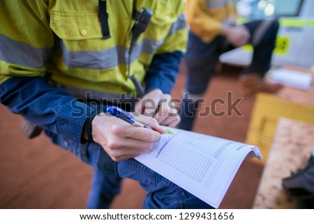 Rope access miner supervisor written checking reviewing inspecting signing issuer the working in confined space permit prior to work on construction mine site Perth, Australia  Royalty-Free Stock Photo #1299431656