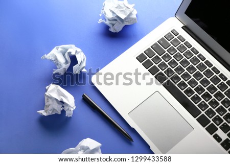 Laptop and crumpled paper on color background. Mistake concept
