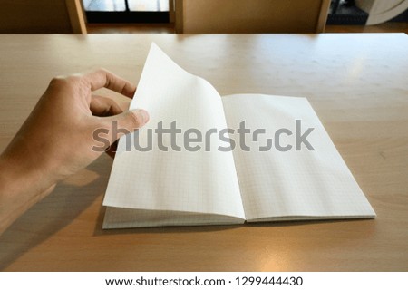 man hand open Grid book on the table