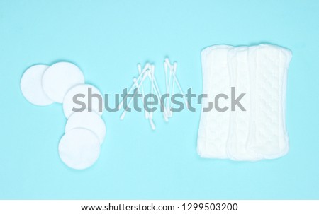 Hygiene products on blue pastel background. Cotton pads, women's pads, cotton ear sticks. Top view, flat lay
