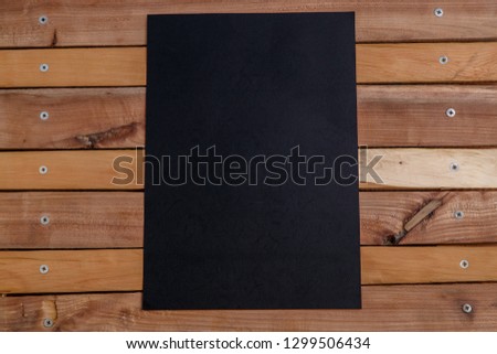 Black paper on a natural wooden background. View from above.