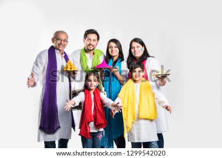 indian family celebrating holi festival with sweet laddu gifts and colours in plate. isolated over white background. selective focus meaning