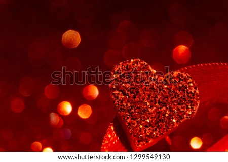 Valentine's day greeting card. Composition with gift, giftbox, red hearts on red surface. Space for text. Red love concept background with defocused lights. Heart shape.