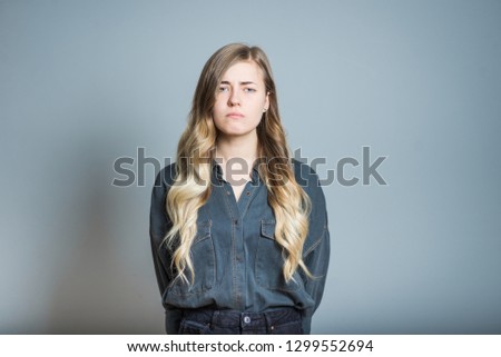 Beautiful blonde girl offended isolated on gray background