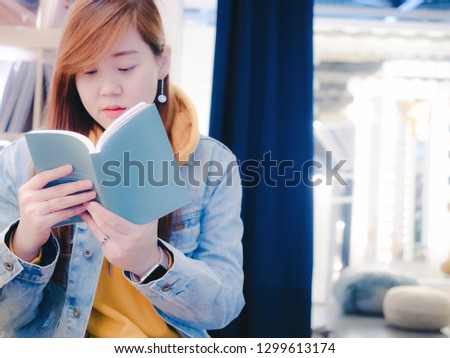 woman relax and lifestyle concept from beauty asian female in blue vintage jean during read her favourite book with happy feeling