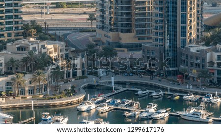 Luxury Dubai Marina canal with passing boats and promenade with palms timelapse, Top view from above at evening before sunset. Dubai, United Arab Emirates