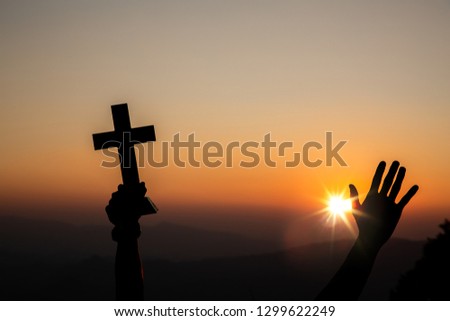 hands of christian holding cross and  worship with light sunset background. christian silhouette concept.