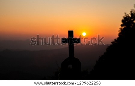 Christian cross in hands with light sunset background. christian silhouette concept.