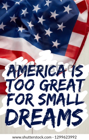 united states flag with america is too great for small dreams quote on white wooden surface