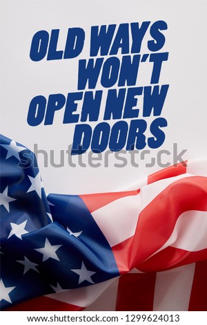 top view of united states of america flag and old ways wont open new doors quote on white surface 