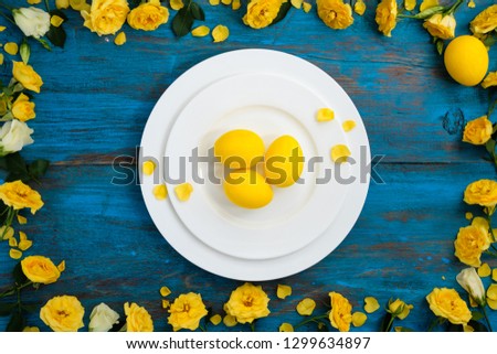Easter table setting on blue wooden background with yellow spring flowers and eggs
