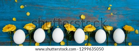 Frame made of flowers and eggs on a blue wooden background

