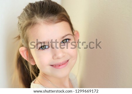 portrait of a little caucasian white beautiful brunette girl with pony tail on neutral background. smiling green eyed happy girl with cute protruding ears. Kid expression attractive face
