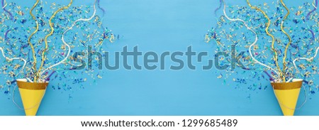 Party colorful confetti and clown hat over blue wooden background . Top view, flat lay
