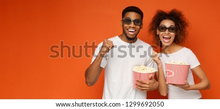 Wow! Millennial african-american couple enjoying 3d technology movie, holding popcorn buckets, orange panorama background with empty space