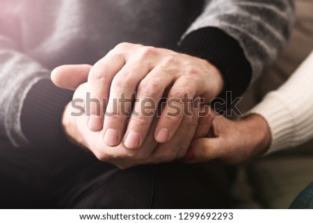 Love and support. Elderly people tenderly hold hands, closeup