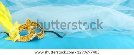 Banner of elegant and delicate gold venetian mask over turquoise silk and chiffon background