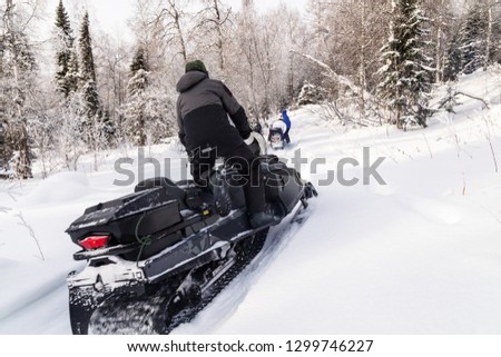 Athletes on a snowmobile moving in the winter forest in the mountains of the Southern Urals.