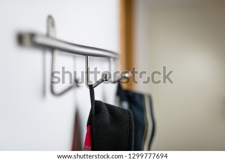 Dark mens jackets hanging on a hook in hause, on a wall hanger.
