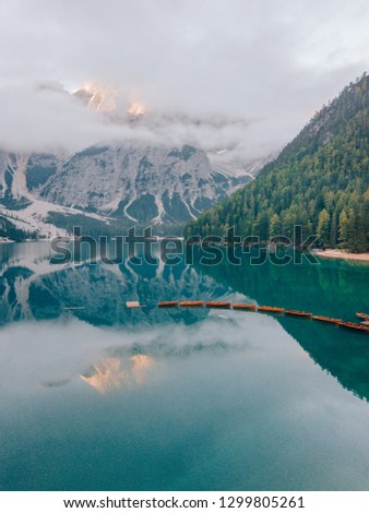 Aerial Shot of Braies Lake in Dolomites mountains forest trail in background, Sudtirol, Italy. Also known as Lago di Braies. The lake is surrounded by forest which are famous for scenic hiking trails