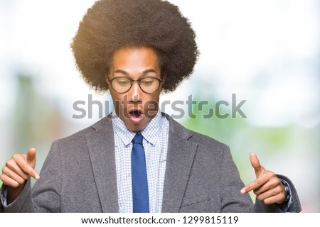 Young african american business man with afro hair wearing glasses Pointing down with fingers showing advertisement, surprised face and open mouth
