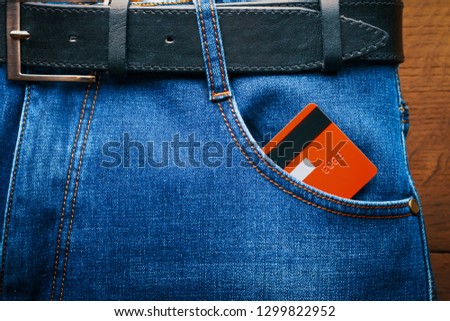 Plastic card in the front pocket of blue jeans.