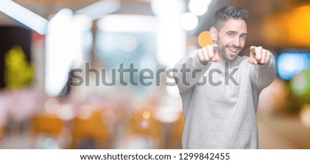 Young handsome man wearing sweatshirt over isolated background Pointing to you and the camera with fingers, smiling positive and cheerful