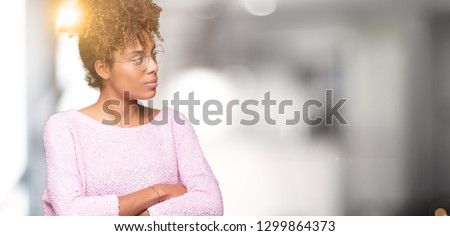 Beautiful young african american woman wearing glasses over isolated background smiling looking to the side with arms crossed convinced and confident