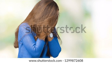 Young beautiful brunette woman wearing blue sweater over isolated background with sad expression covering face with hands while crying. Depression concept.