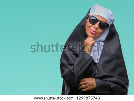 Middle age senior catholic nun woman wearing sunglasses over isolated background with hand on chin thinking about question, pensive expression. Smiling with thoughtful face. Doubt concept.